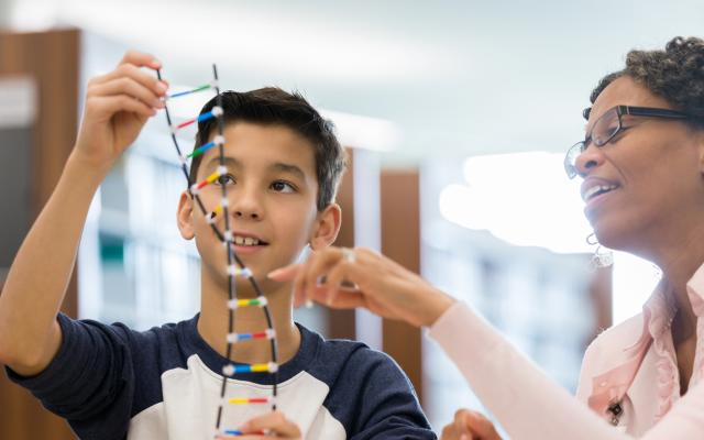 Jongen kijkt met vrouw naar DNA-helix model.