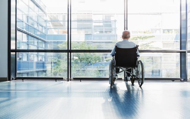 Man in rolstoel voor raam