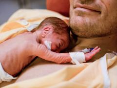 Premature baby op borst van man